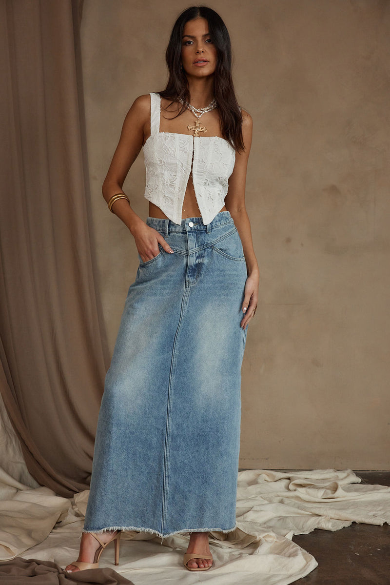 Light wash denim maxi skirt styled with a white crop top and heels.