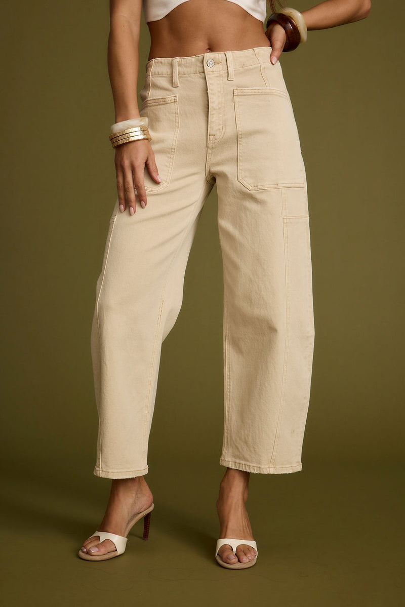 Full-length view of the beige jeans showing the drape and movement.