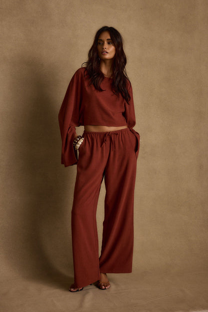 Full-length view of the rust pants showing the drape and movement.