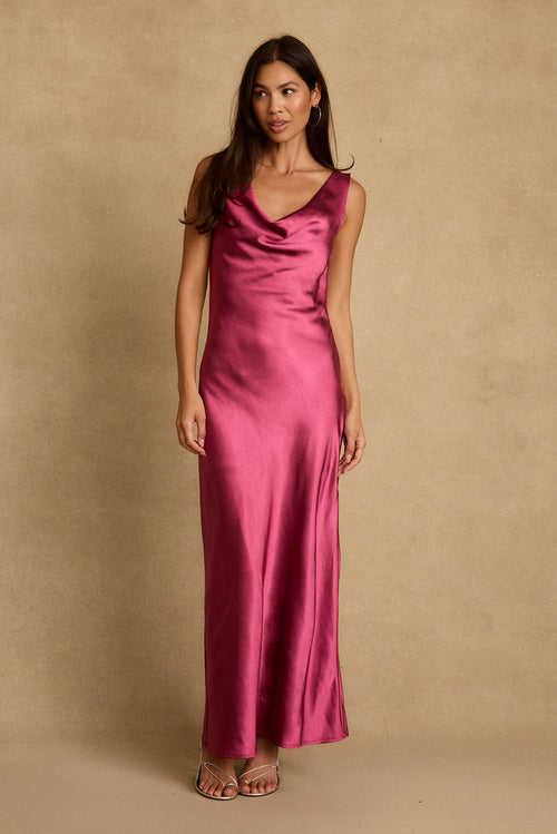 Model wearing the 12th Tribe Dolce Fuchsia Satin Maxi Dress in a bold fuchsia satin. Featuring a fluid maxi silhouette and high-shine finish. Style with heels for bachelorette parties, weddings, and evening outings.