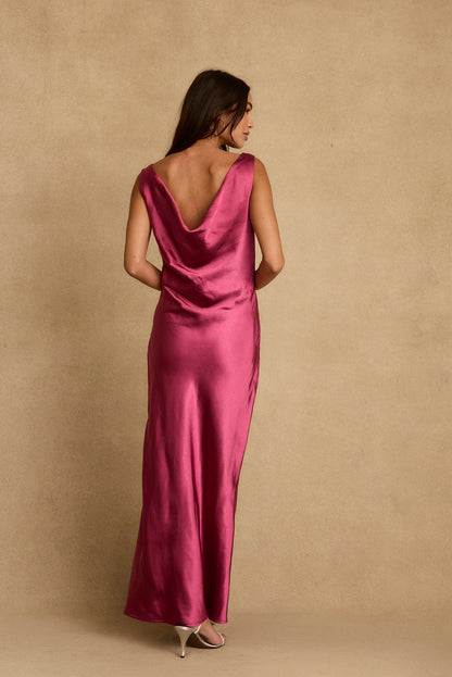 Back view of fuchsia satin maxi dress with draped cowl back and silver heels.