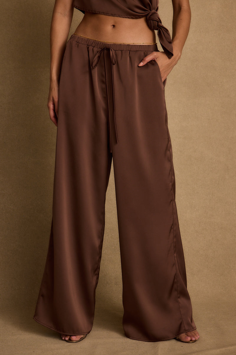 Back view of the espresso satin pants showing the silhouette and fit.