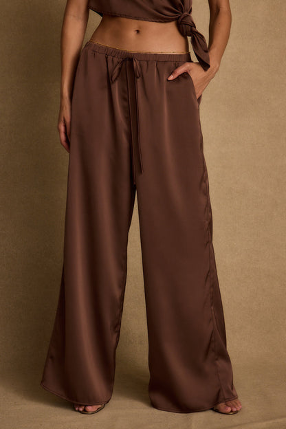 Back view of the espresso satin pants showing the silhouette and fit.