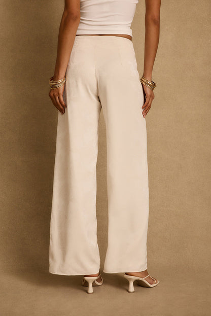 Back view of ivory floral jacquard wide-leg trousers styled with heeled sandals and gold bangles.