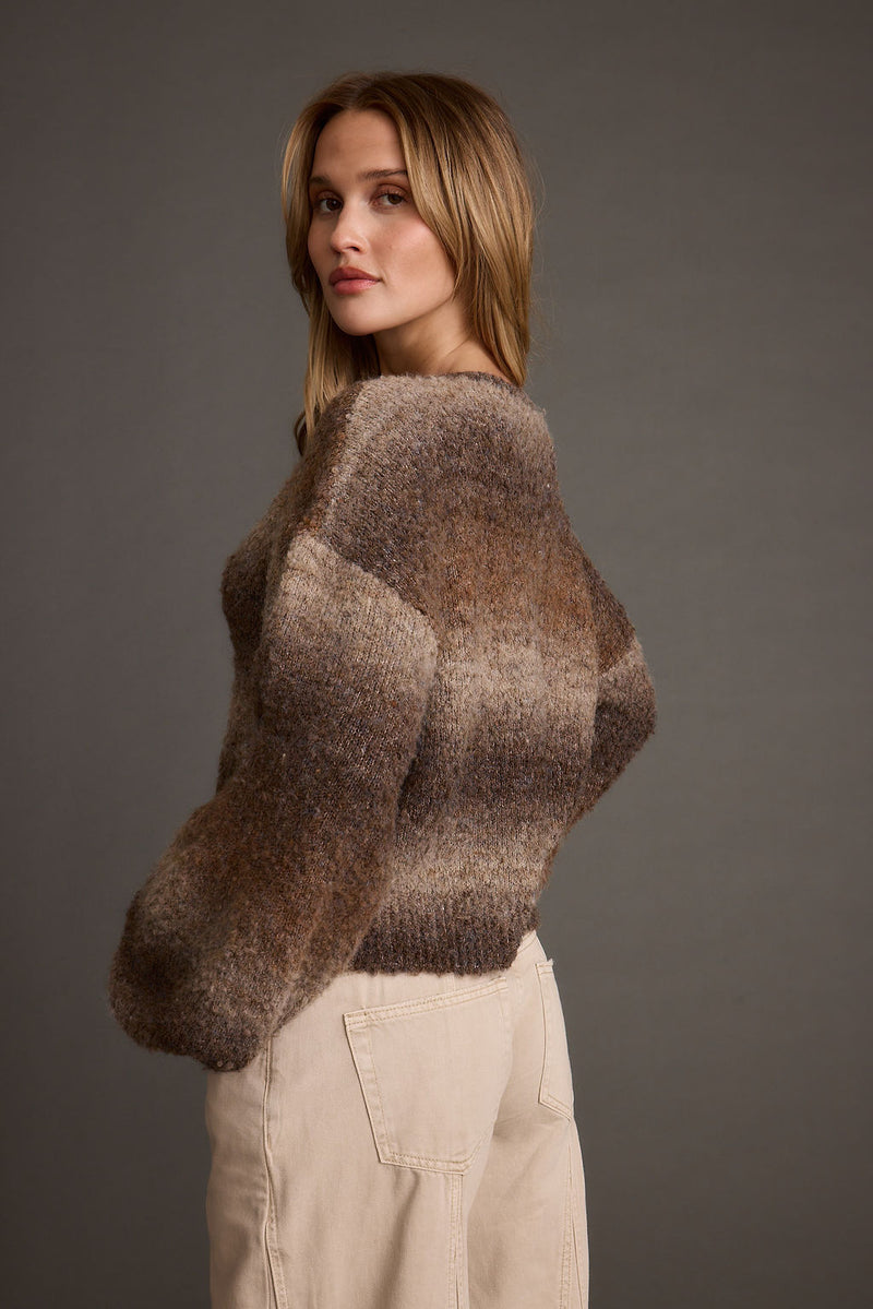 Side view of ombre balloon sleeve sweater in brown and green tones with cream jeans.