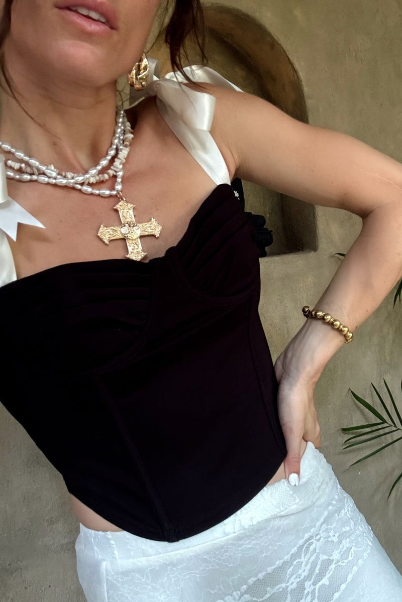 Black corset tank with white ribbon straps, styled with gold cross necklace and lace skirt.