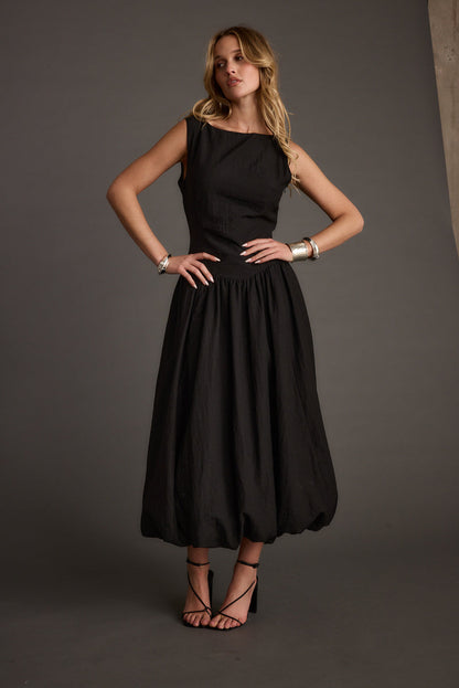 Full-length view of the black midi dress showing the drape and movement.