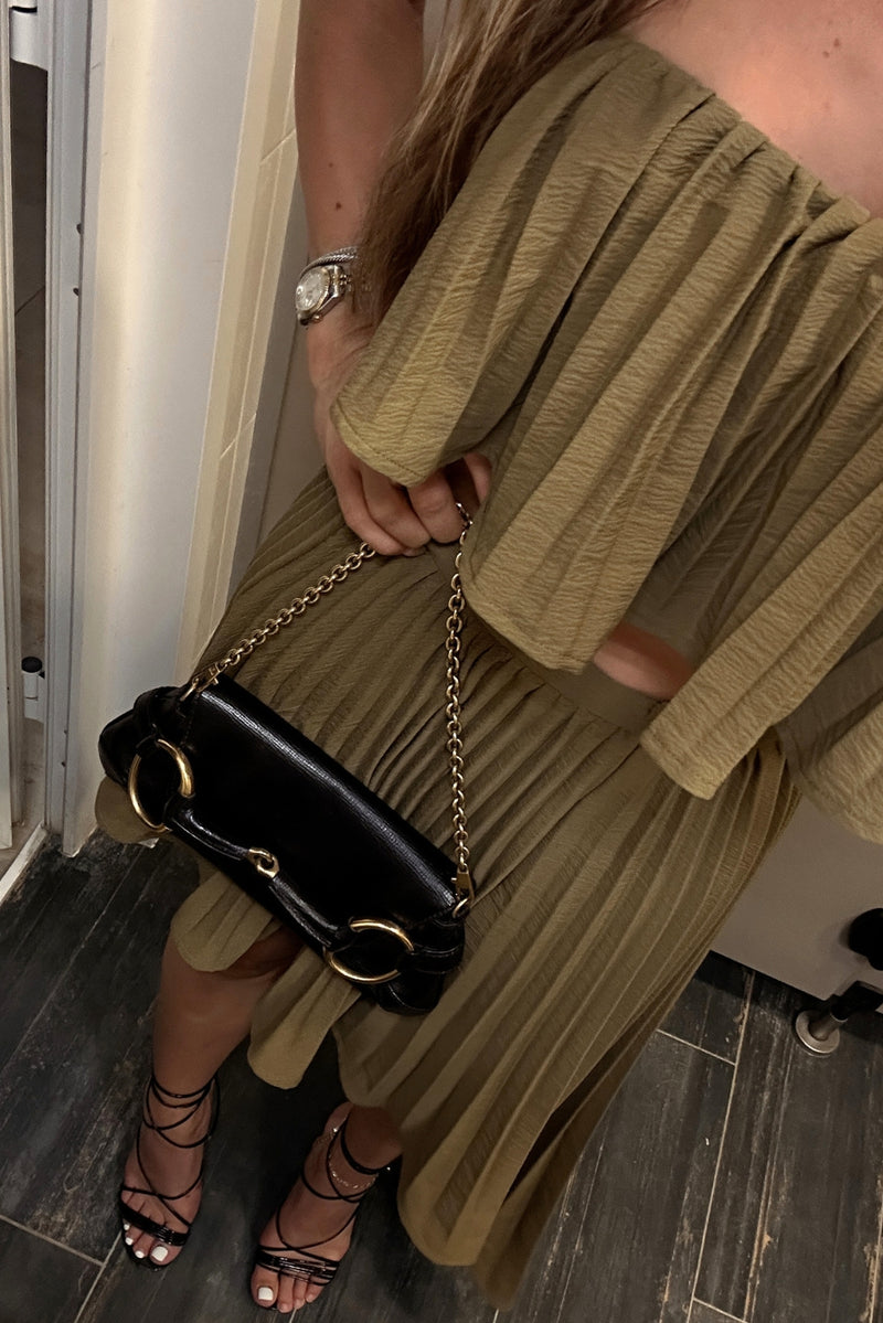 Olive pleated strapless crop top styled with matching midi skirt, black bag and lace-up heels.