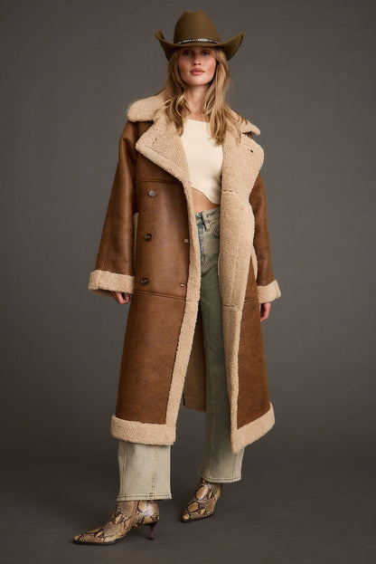 Full-length view of the brown jacket showing the drape and movement.