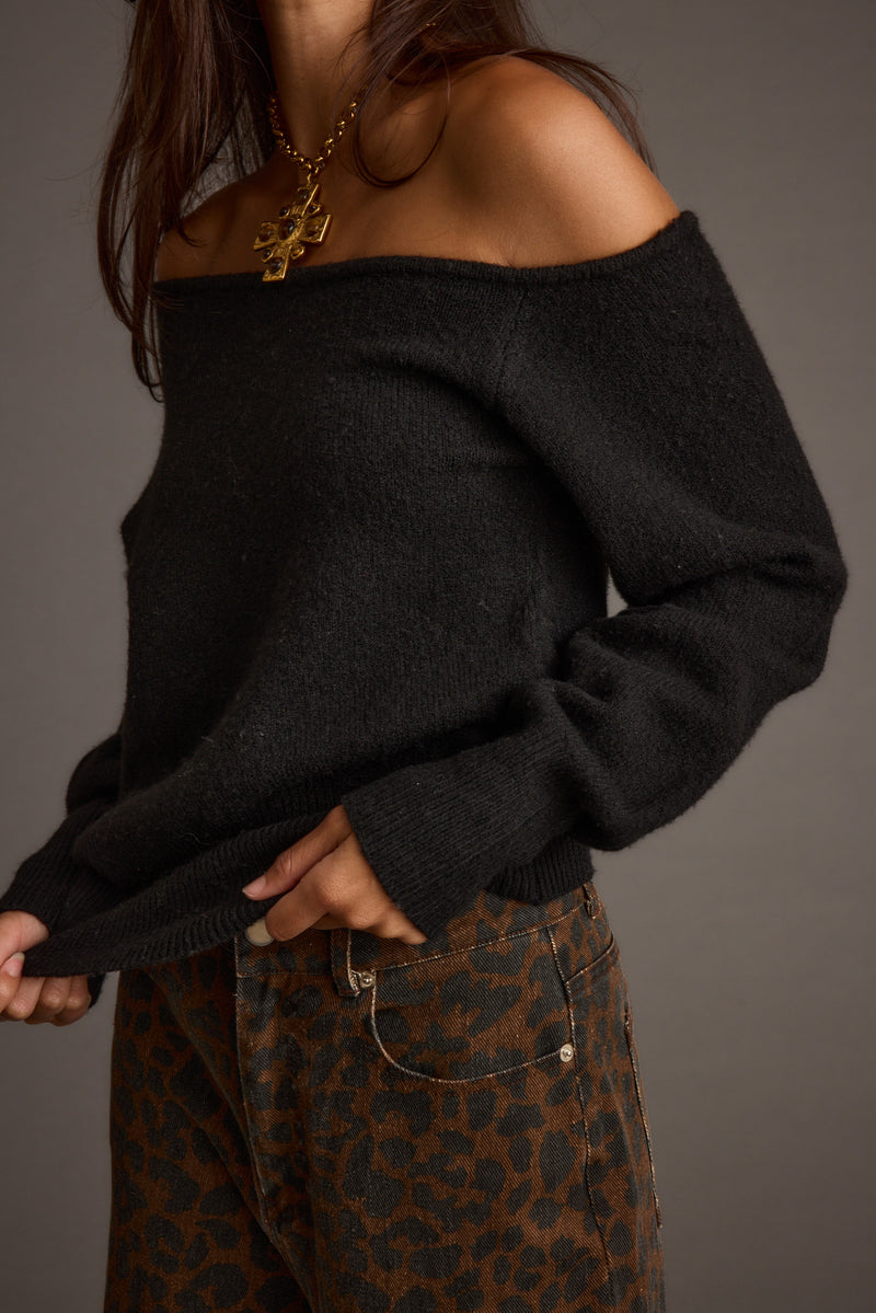 Full-length view of the black sweater showing the drape and movement.