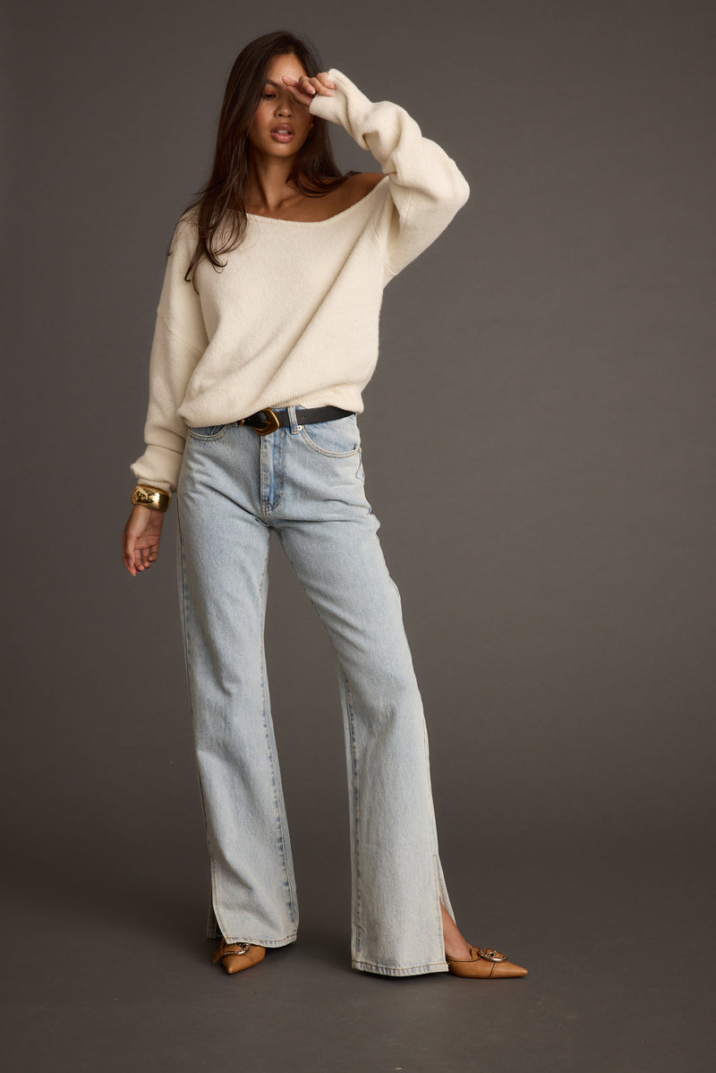Full-length view of the cream sweater showing the drape and movement.