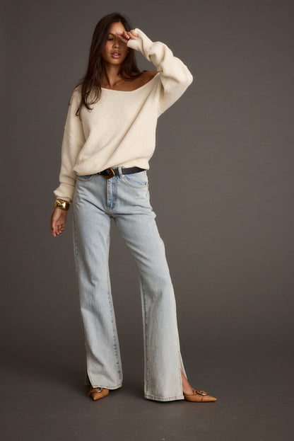 Full-length view of the cream sweater showing the drape and movement.