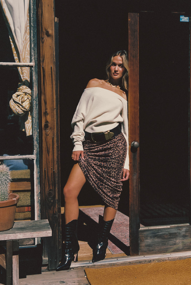 Lifestyle shot of the cream sweater styled for day-to-night versatility.