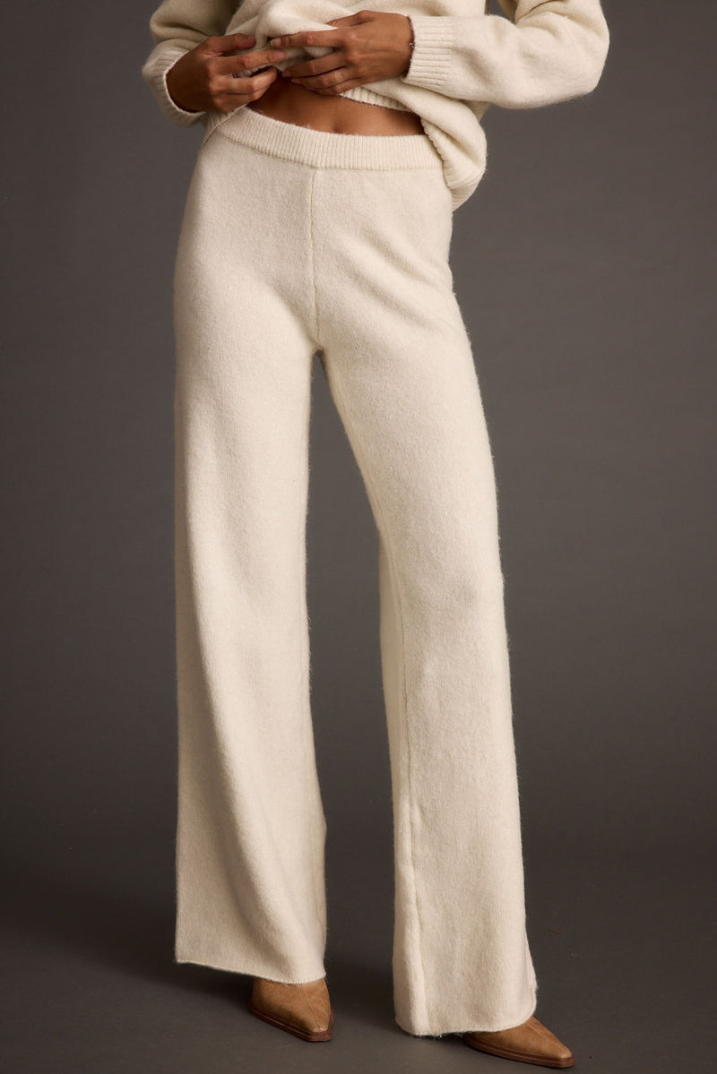 Full-length view of the ivory sweater showing the drape and movement.