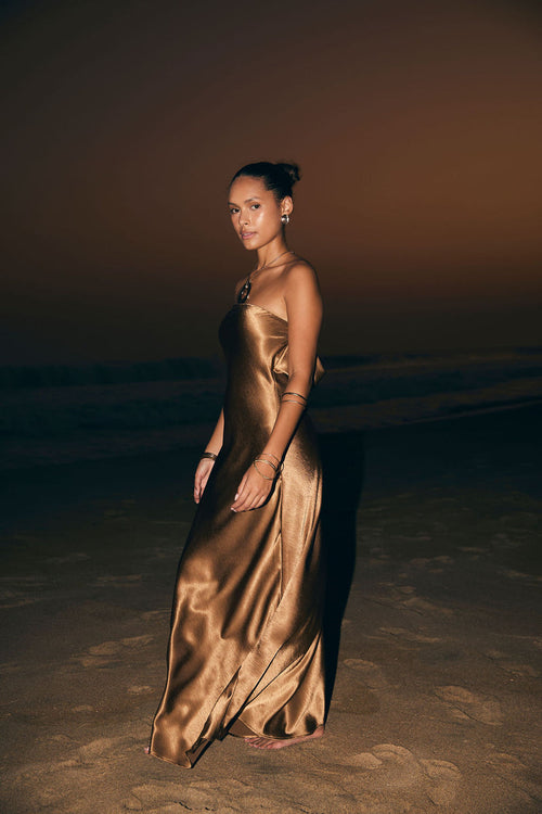 Model wearing the 12th Tribe Natalia Bronze Strapless Maxi Dress in a rich bronze satin. Featuring a sleek strapless neckline and elegant maxi silhouette. Style with strappy heels for bachelorette parties, vacation dinners, and bachelorette celebrations.