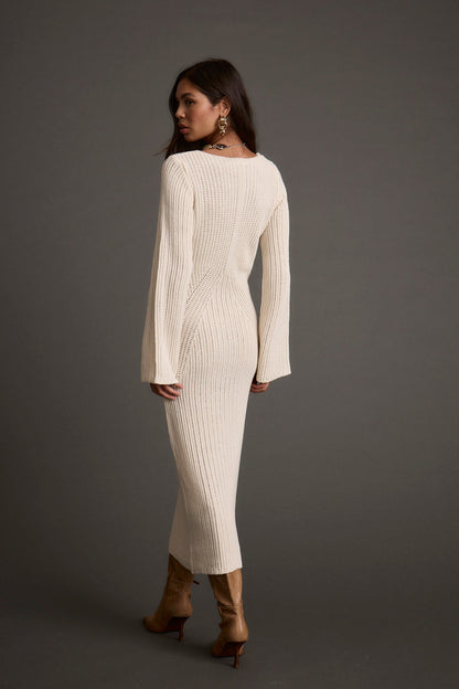 Lifestyle shot of the cream sweater dress styled for day-to-night versatility.