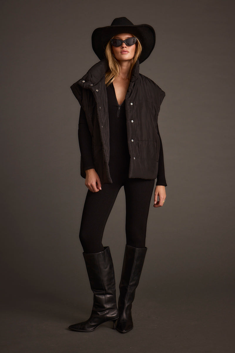 Lifestyle shot of the black jumpsuit styled for day-to-night versatility.