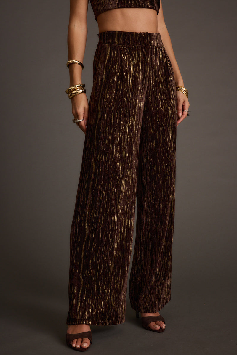 Back view of the espresso velvet trousers showing the silhouette and fit.