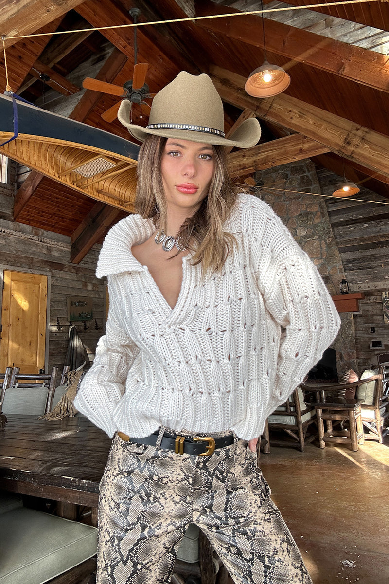 Full-length view of the cream sweater showing the drape and movement.