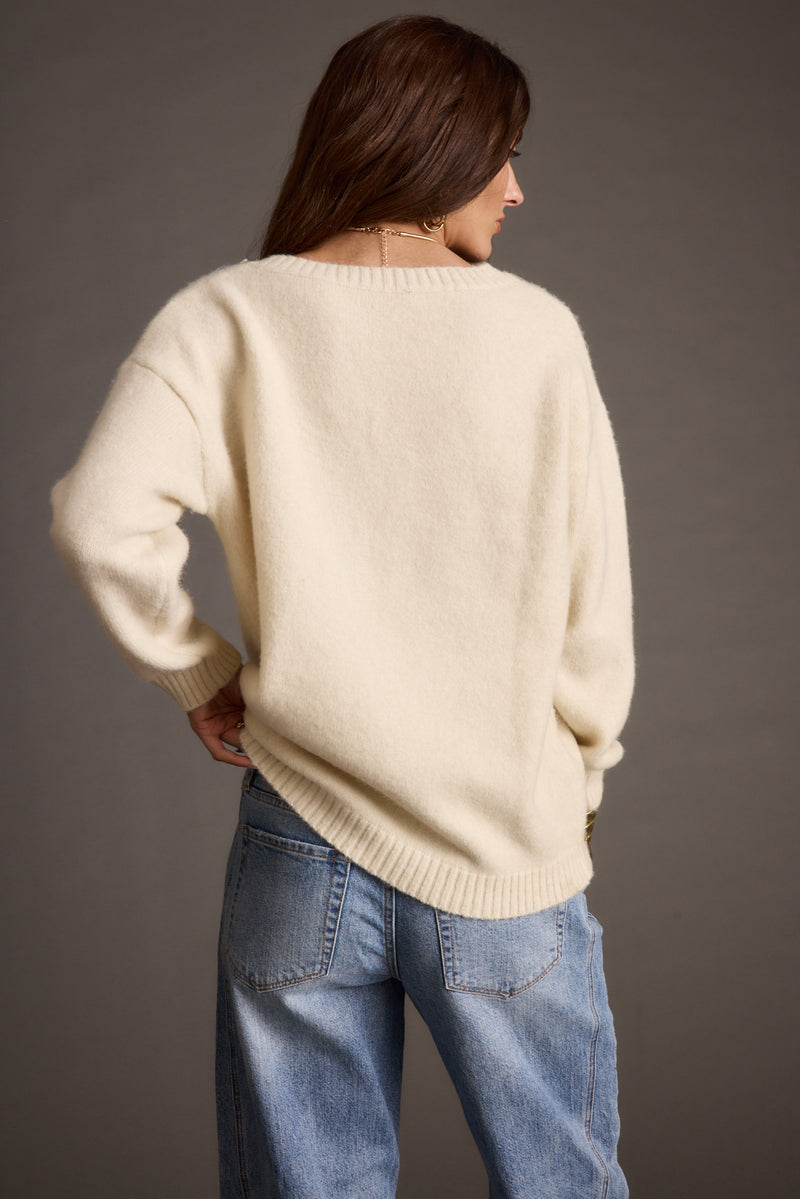 Full-length view of the ivory sweater showing the drape and movement.