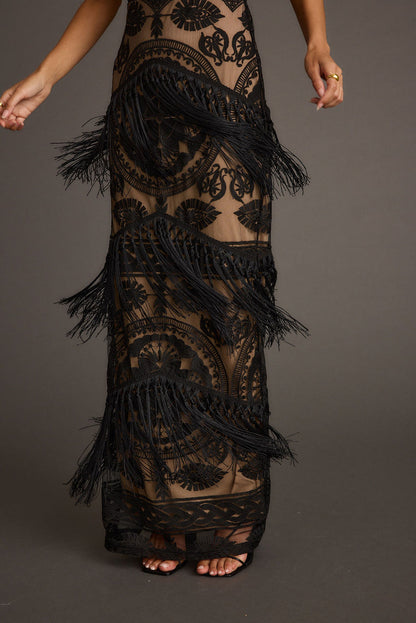 Detail of black lace fringe maxi dress skirt over nude mesh, with tiered fringe.