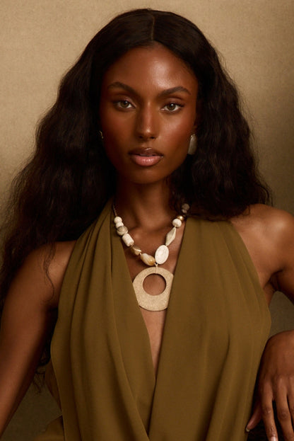 Olive green halter dress styled with a beaded gold pendant necklace, resort outfit for women.