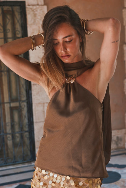 Olive satin scarf-neck halter top styled with gold sequin skirt and bangles.