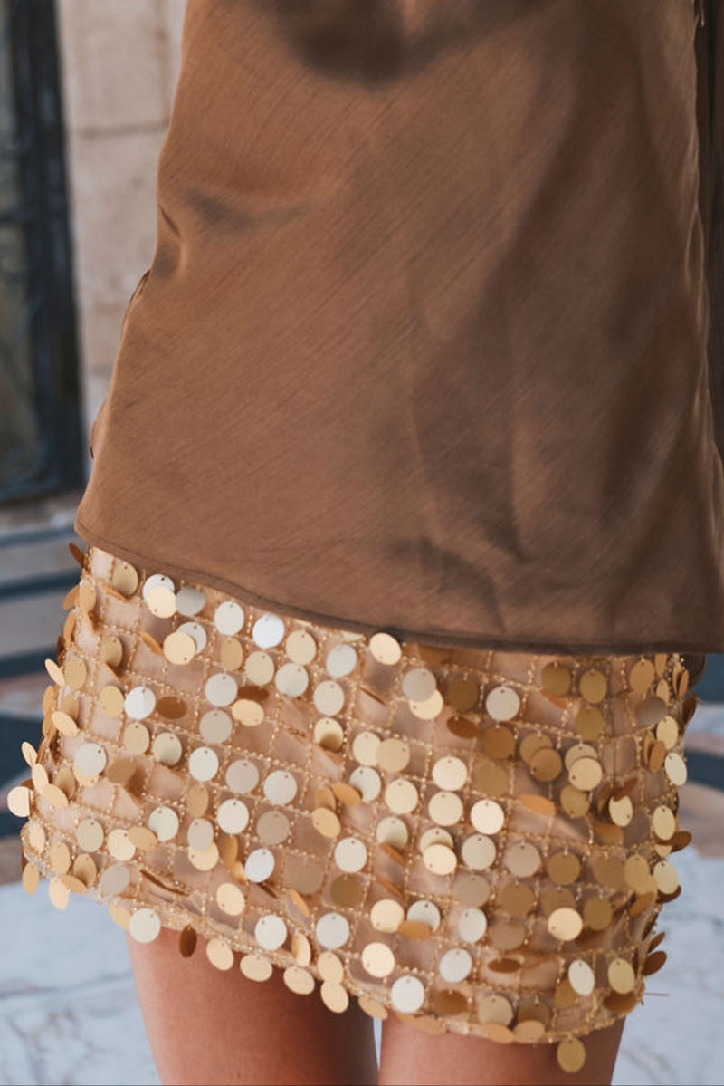 Gold paillette sequin mini skirt paired with a brown satin top, detail view.