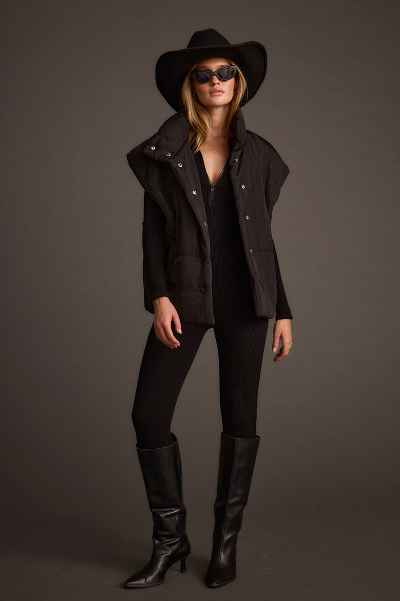 Full-length view of the black vest showing the drape and movement.
