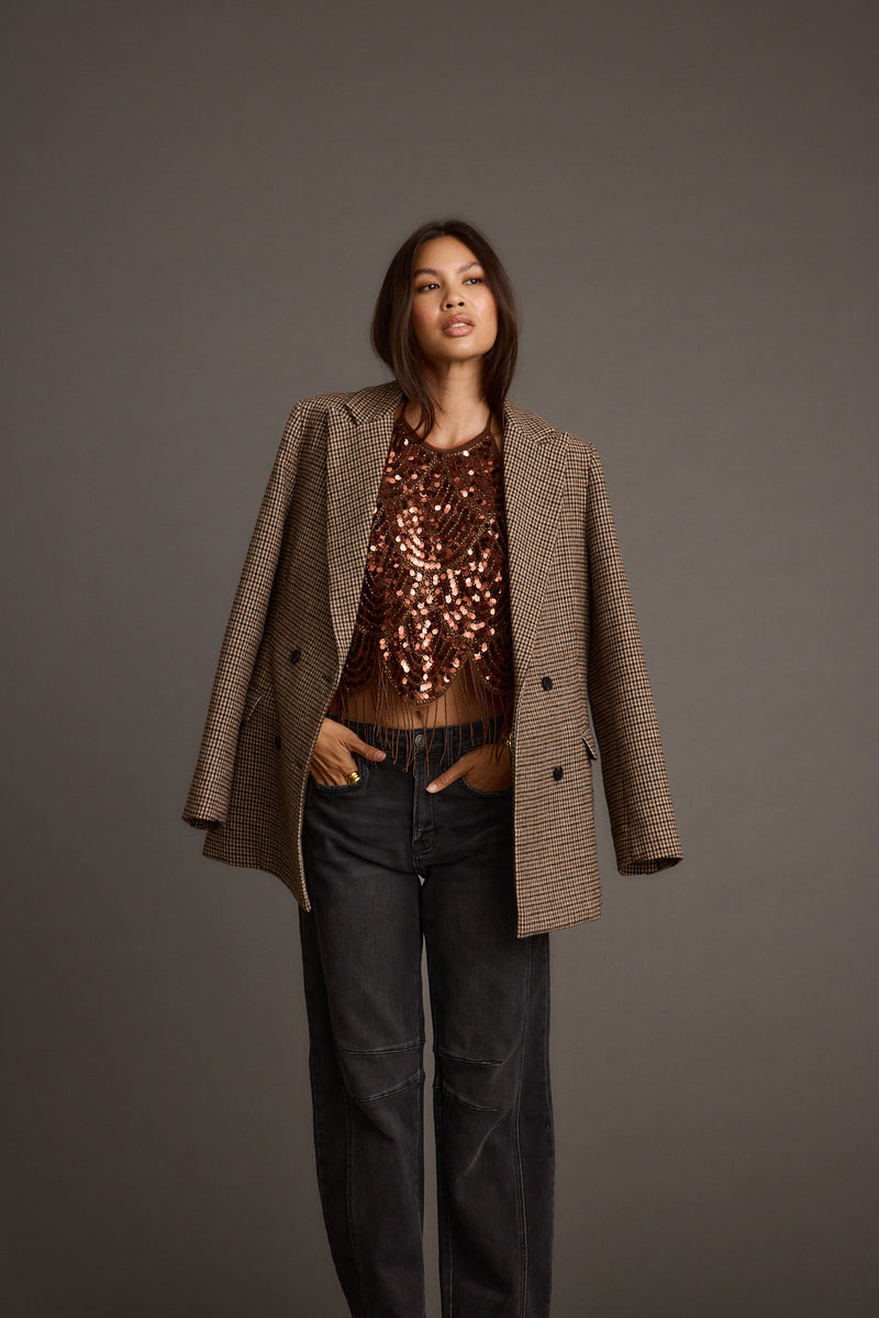Brown plaid blazer worn open over a sequin top with black jeans.