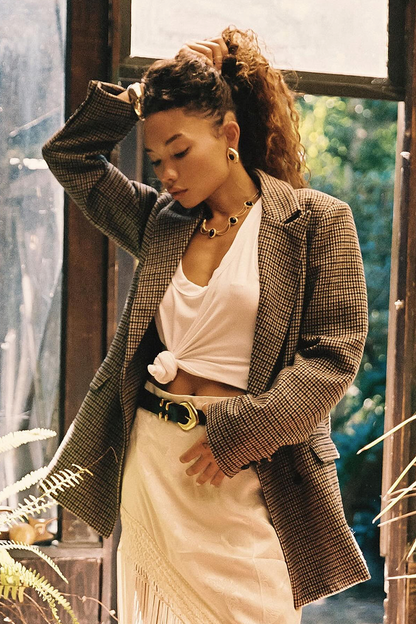 Brown plaid blazer styled over a white tie-front top with cream skirt.